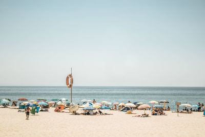 Panoramic view of people at beach against clear sky