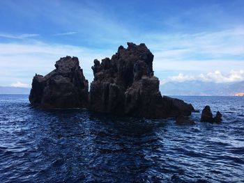 Rocks in sea against sky