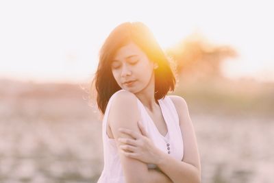 Beautiful young woman standing on land against sky