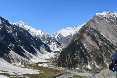 Scenic view of snow covered mountains against clear blue sky