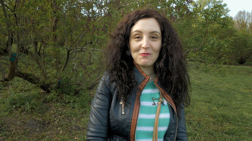 Portrait of beautiful young woman standing against trees