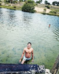 High angle portrait of shirtless man standing in lake