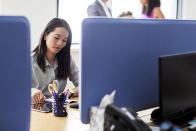 Confident businesswoman reading diary while sitting at desk in creative office