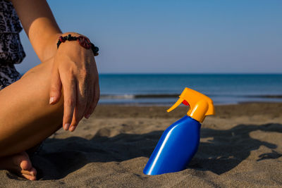 Midsection of person on beach against sky