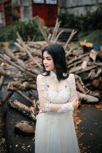 Portrait of young woman standing against tree trunk