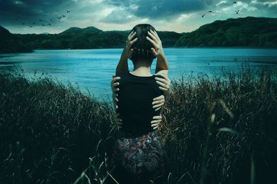 Young woman standing by lake against sky