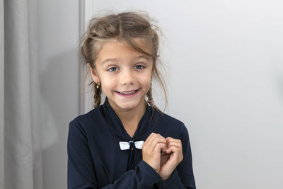 Portrait of smiling girl standing against wall