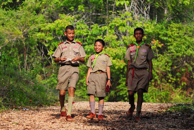 Full length portrait of friends standing in forest