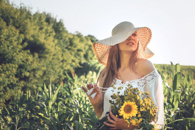 Beautiful young woman standing by flowering plants