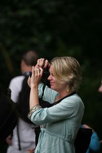 Woman photographing through smart phone outdoors