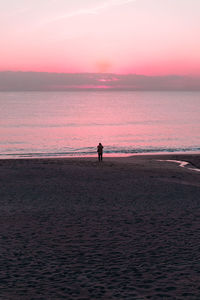 Silhouette man standing on beach against sky during sunset