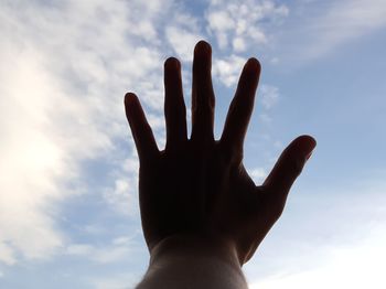 Low angle view of human hand against sky