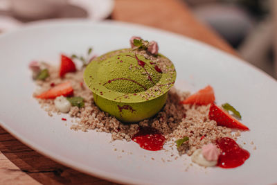 Delicious sweet pistachio dessert with fresh strawberry pieces, jam and cookie crumbs. side view