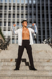 Man wearing fully unbuttoned shirt while standing on steps