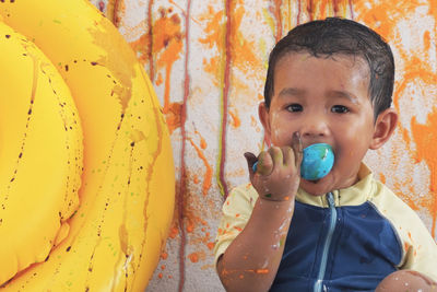 Portrait of smiling cute boy painting wall 