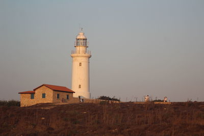 Lighthouse amidst buildings against sky