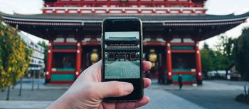 Close-up of cropped hand photographing temple with smart phone