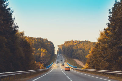 Road amidst trees against clear sky during autumn