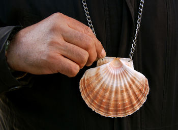 Cropped image of man holding seashell pendant