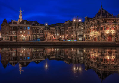 Illuminated buildings reflecting in river at dusk