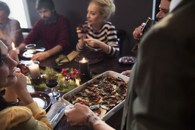 Woman serving food to happy friends at table during christmas party