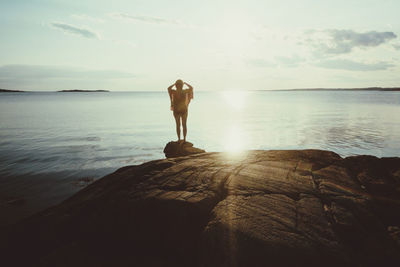 Rear view of woman walking at beach against sky