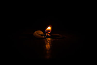 Close-up of illuminated candle in darkroom