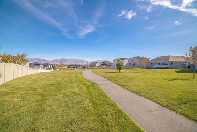 Scenic view of field by houses against sky