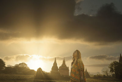 Woman standing against sky during sunset