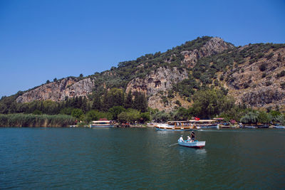 Rowing boat with tourists floating on the river near the lycian tombs in the summer