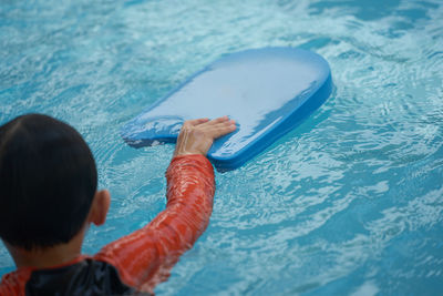 Rear view of boy swimming in pool