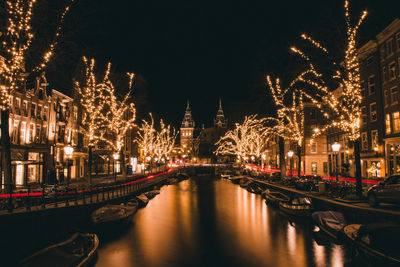 Illuminated bridge over canal in city at night