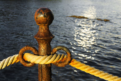 Close-up of rope attached to bollard against sea