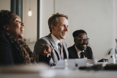 Smiling businessman discussing with colleagues during meeting at office