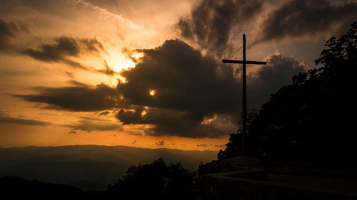 Low angle view of silhouette trees against dramatic sky during sunset