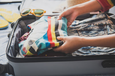 Cropped hands of woman packing suitcase at home