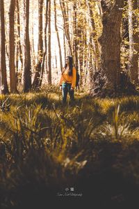 Woman standing on field in forest