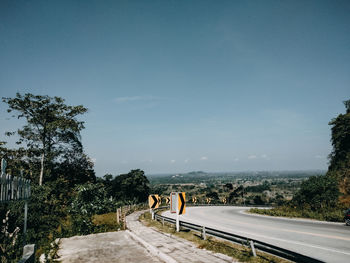 Road by trees against sky