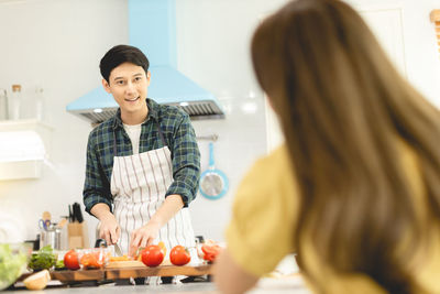 Smiling young woman standing in kitchen at home