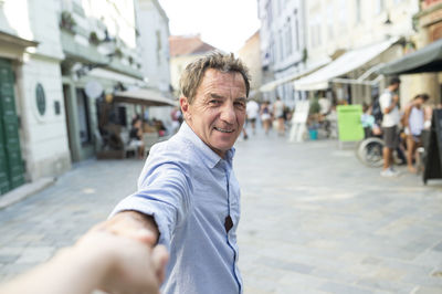 Slovakia, bratislava, portrait of happy senior man holding hand on the street