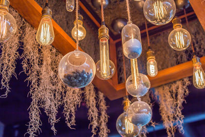 Low angle view of illuminated pendant lights hanging from ceiling