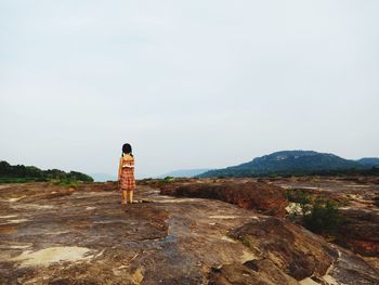 Rear view of man standing on mountain against sky