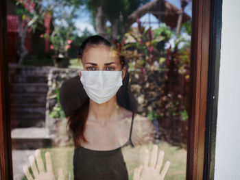 Portrait of young woman looking through window