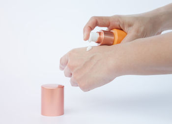 Close-up of hand holding bottle against white background