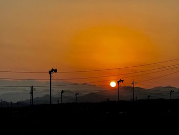 Silhouette electricity pylon against romantic sky at sunset