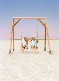 Children playing on sea against clear sky