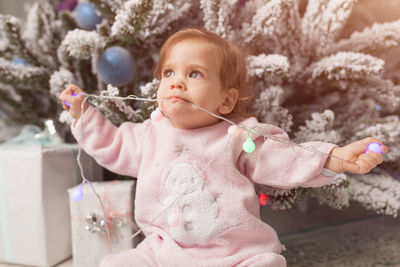 Cute girl eating wire of christmas lights at home