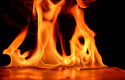 Close-up of burning candle against black background