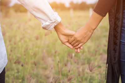 Midsection of couple holding hands