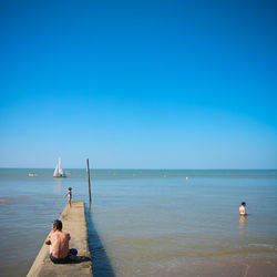 People at beach against clear sky